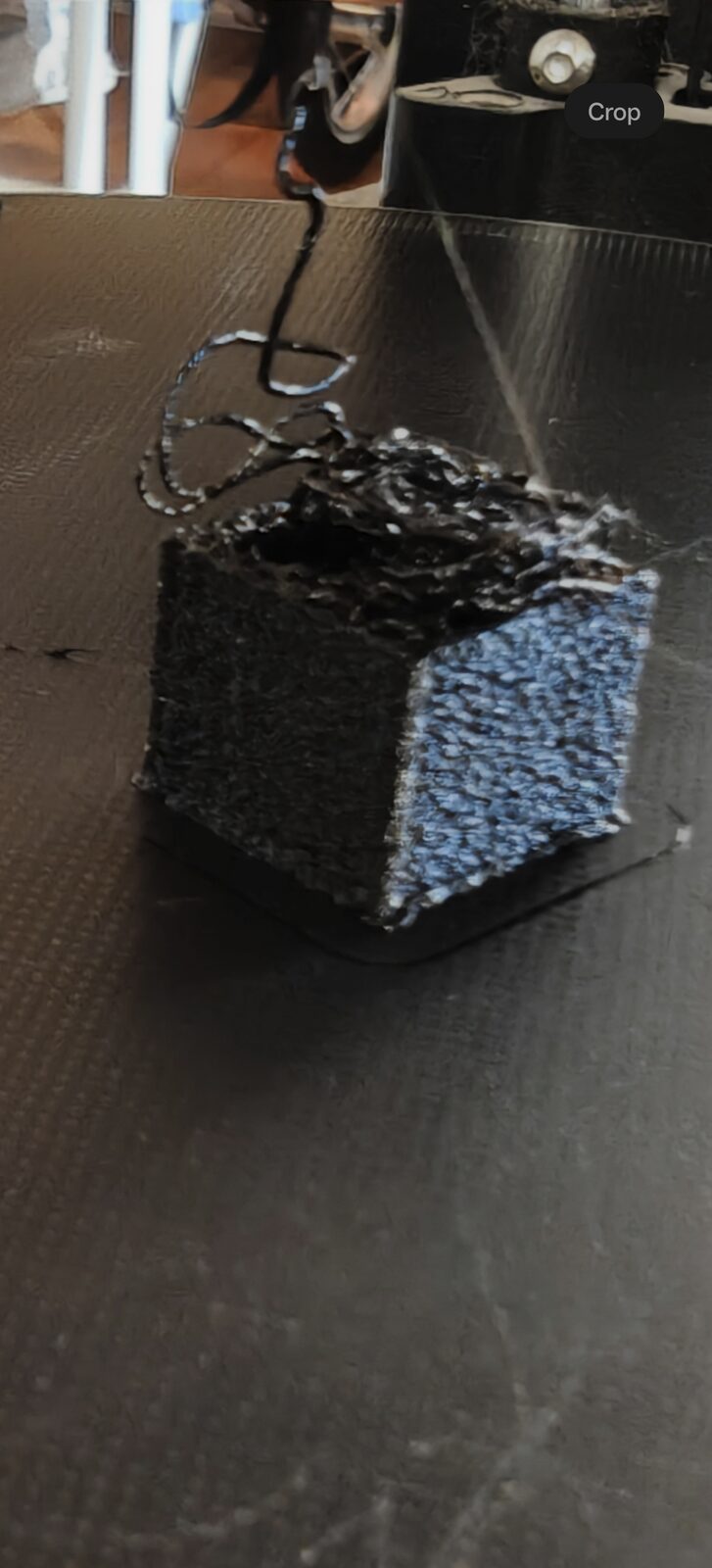 Cube de 20 mm en PETG noir imprimé sur la FLSun QQ-S, parois mousseuses et irrégulières, filaments qui pendent : filament humide